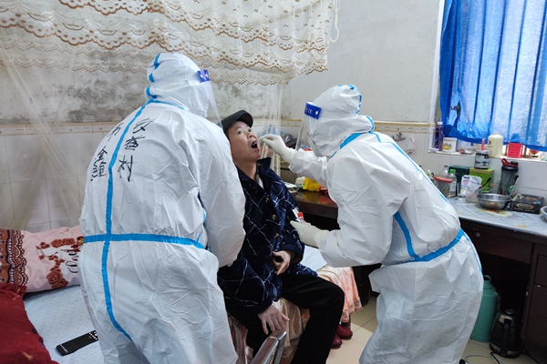 图为韦鑫上门为高龄伤残村民进行核酸采集.jpg